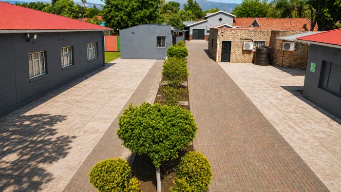 A landscaped central walkway between grey Da Silva Academy buildings with red roofs.